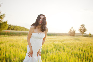 Fototapeta na wymiar pregnant gorgeous brunette woman on the field with wheat and pop