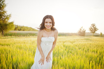 Fototapeta na wymiar pregnant gorgeous brunette woman on the field with wheat and pop