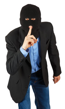 Thief in black mask in suit with finger signaling to be quite