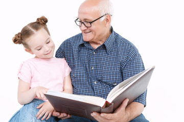 Grandfather reading a book with granddaughter