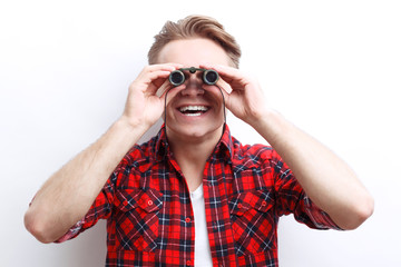 Interested smiling guy looking through binoculars 