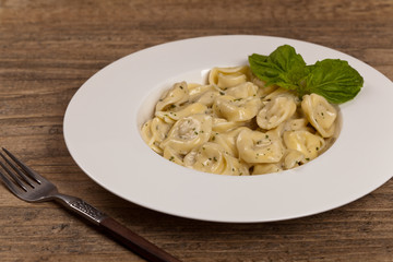 Italian Tortellini Pasta with Alfredo Sauce and Basil. Selective focus.