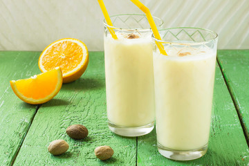 Cold homemade milkshake with ice cream, orange juice and nutmeg