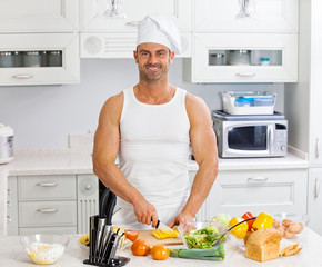 Happy handsome man cooking in kitchen at home.