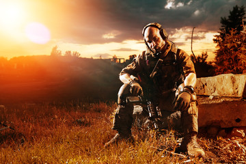 American soldier with the M4 rifle is having a rest. Sunset on t