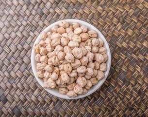 Chickpeas in a white bowl on wooden board