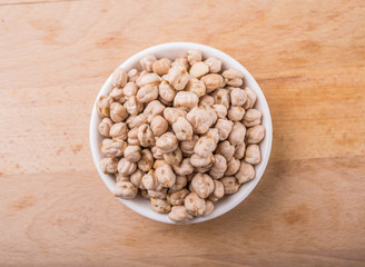 Chickpeas in a white bowl on wooden board