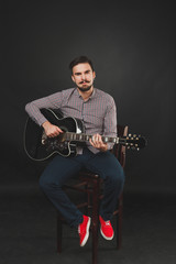 Fototapeta premium handsome guy with beard holding acoustic guitar