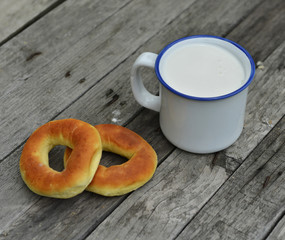 Fresh doughnuts with cup of milk on old wooden table