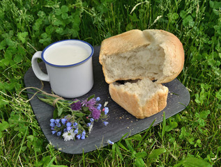Rural still life with mug of milk, loaf of bread and wildflowers 