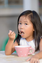 Cute little asian girl eating cereals in morning.