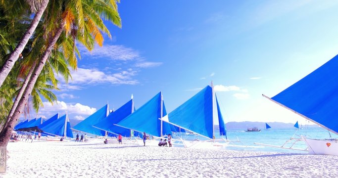 Row of traditional sail boats on sandy beach waiting for tourist to buy a cruise