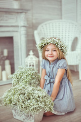 A girl is sitting on the floor near the flowers © Cliplab