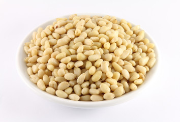 Handful of pine nuts on a white porcelain dish