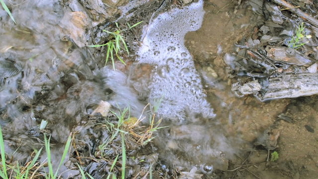 Spring water stream flowing into a small waterfall with stones
