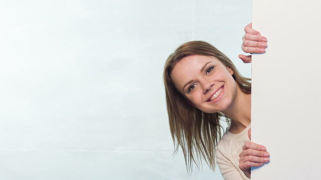 Nice woman peeking from behind wall