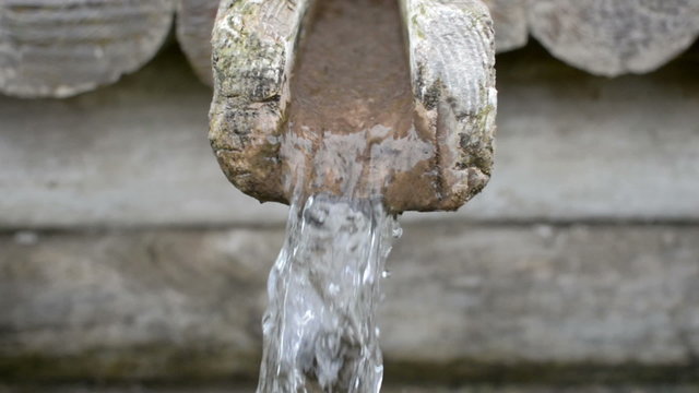Water flowing out of a wooden funnel from a natural spring
