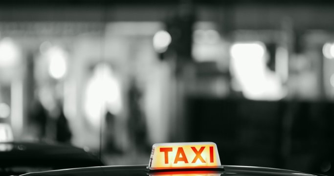 Taxi sign emblem on cab roof close up view. Illuminated taxi label at night 