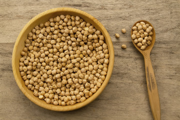 bunch of chickpeas in a bowl and spoon on old wooden background. Indian cuisine