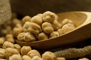 scattered chickpeas from a jute bag with a spoon on old wooden background