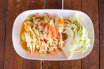 Green papaya salad with salted egg on wood table. Original spicy thai food is the most popular