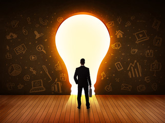 Obraz premium Business man looking at bright light bulb in the wall