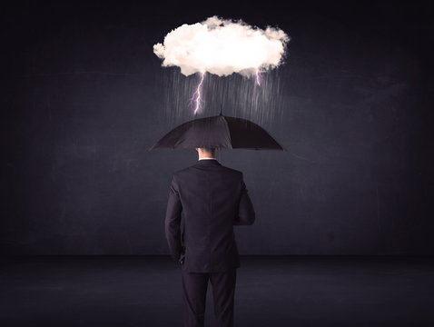 Businessman standing with umbrella and little storm cloud