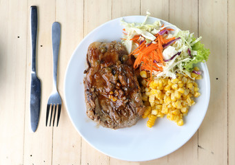 Beef Steak on white dish, plank wood background.