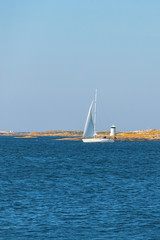 Sailboat with a lighthouse on the rocks