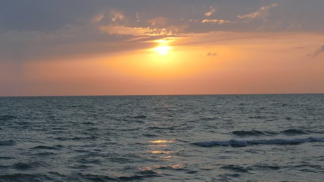 sun sets into the horizon above the sea