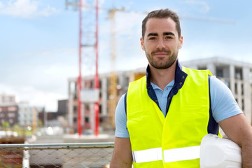 Portrait of an attractive worker on a construction site - obrazy, fototapety, plakaty
