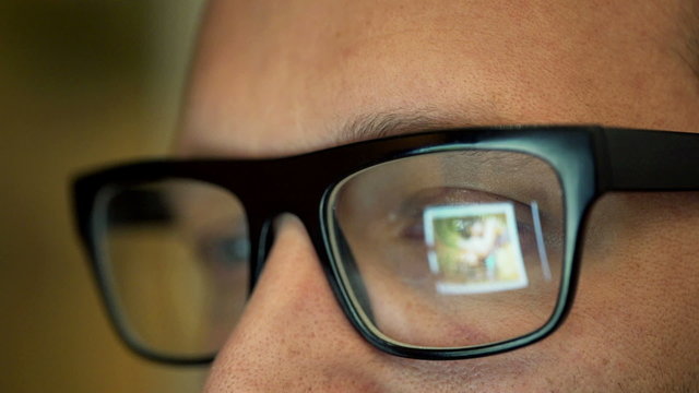 Close up of man in glasses watching photos on tablet computer 
