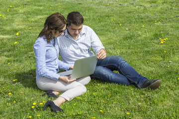 Naklejka na ściany i meble Young people working out. Man and woman casual dress code pant jeans shirt sitting on grass lawn working with laptop computer students learning businessman out of office