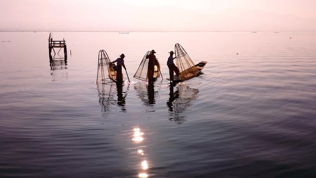 Myanmar, Burma Inle Lake fishermen fishing on traditional boat at sunset