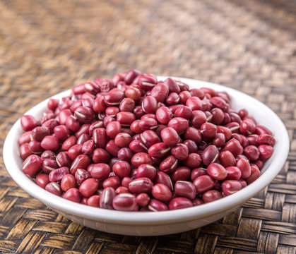 Red adzuki beans in white bowl over wicker background