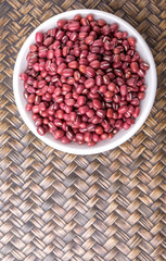 Red adzuki beans in white bowl over wicker background
