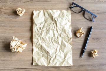 Crumpled paper balls with eye glasses on wood desk