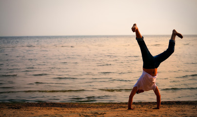 Fototapeta na wymiar man doing handstand on beach
