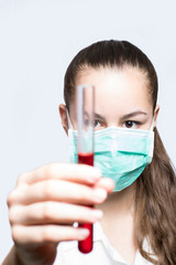 Girl in a mask holding test tube with red liquid - science concept