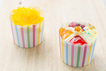 Two cupcakes on a wooden table.