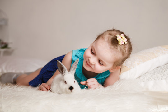 Cute little girl playing with white rabbits