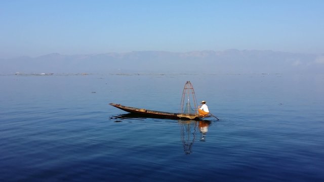 Myanmar, Inle Lake traditional fisherman from Intha ethnic group of Shan state fishing on wooden boat. Beautiful and scenic landscape
