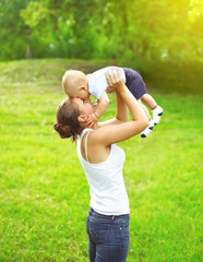 Fototapeta premium Happy mother playing and having fun with baby outdoors in sunny