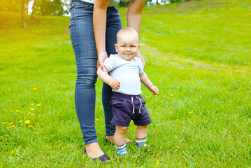 Mother and baby walking together on the grass in summer day