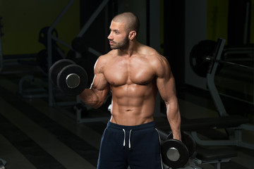 Fototapeta na wymiar Male Bodybuilder Doing Heavy Weight Exercise For Biceps