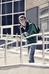 Teen boy with backpack against a school building