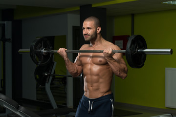 Fototapeta na wymiar Bodybuilder Exercising Biceps With Barbell