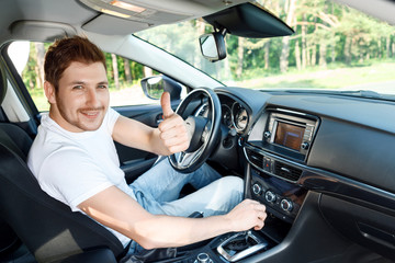 Obraz premium Smiling man thumbing up inside car