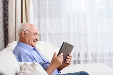Senior man  sitting and holding tablet