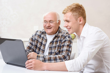 Grandfather and grandson sitting with laptop 